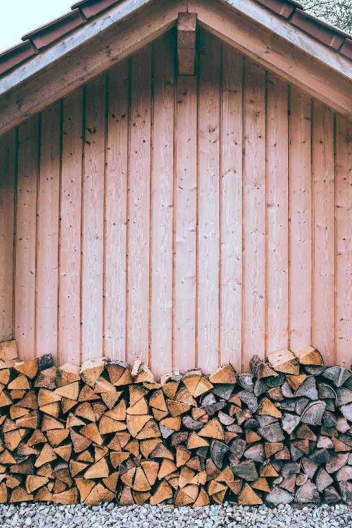 Tas de bûches de bois adossées a une cabane en bois